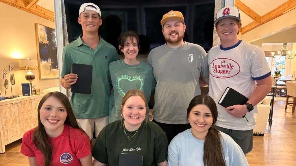 Youth pastor and his wife pose with a group of co-ed high school seniors