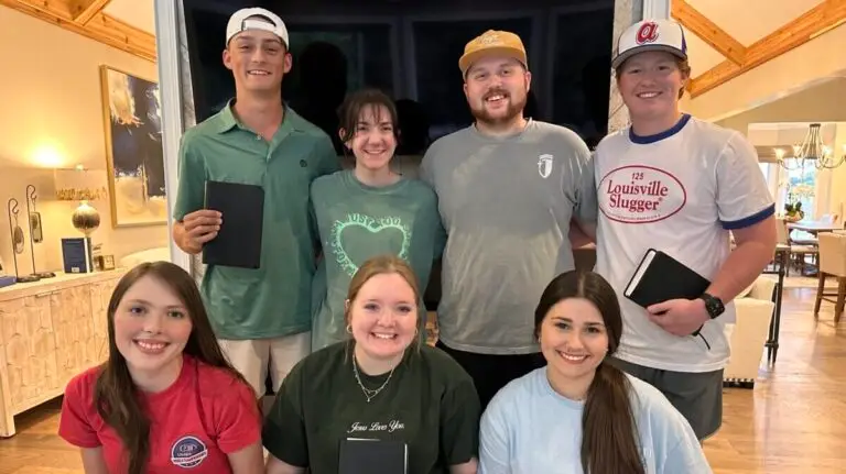 Youth pastor and his wife pose with a group of co-ed high school seniors