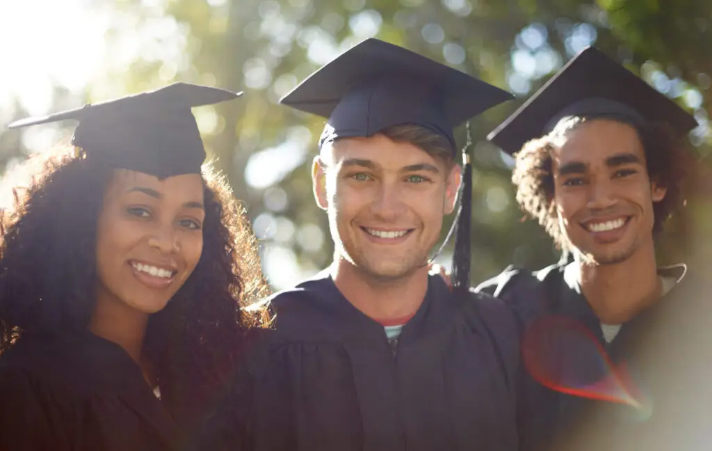 Portrait of three happy students on graduation day.