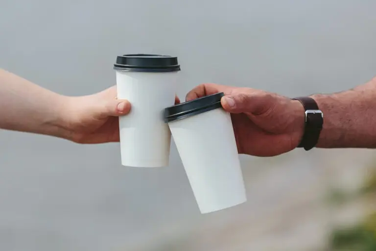 Two men cheers disposable coffee cups