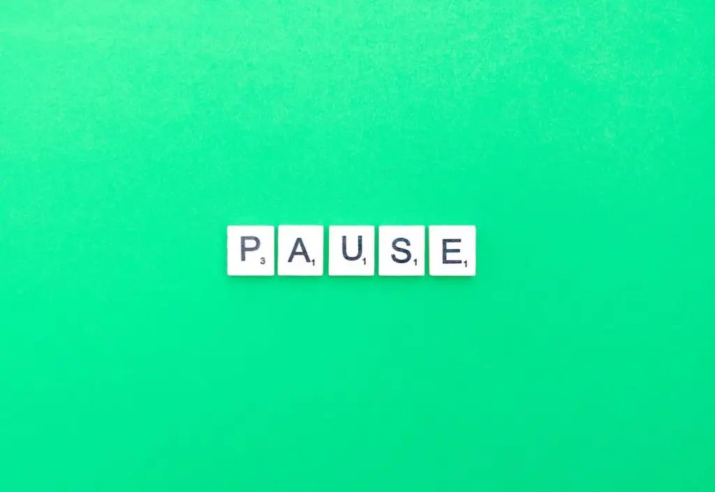 Scrabble letters spelling PAUSE on a bright green background.
