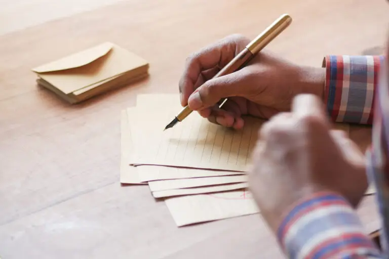 rear view of a man writing a letter on a table